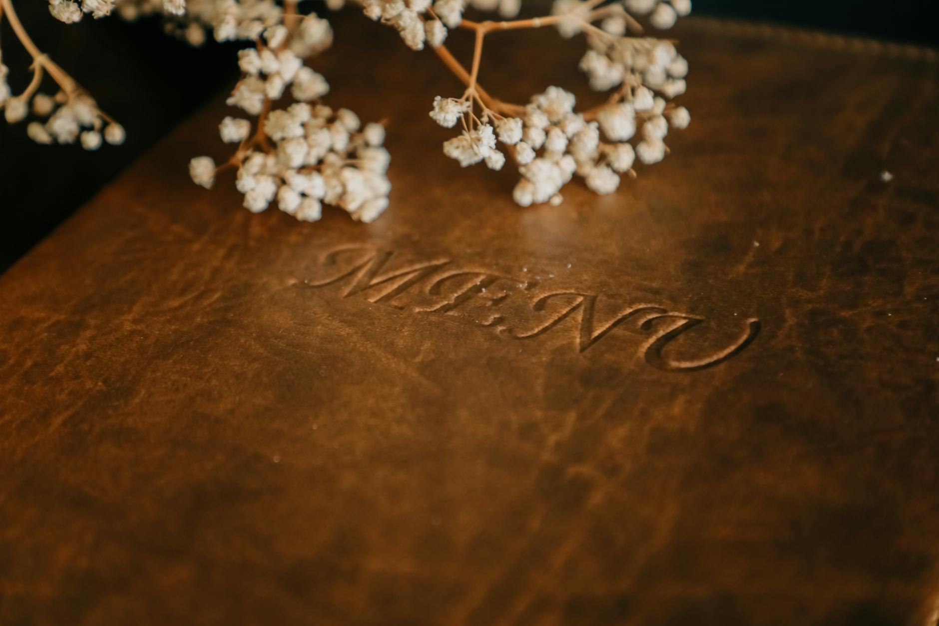 Brązowe skórzane menu ślubne z gipsówką na eleganckim stole