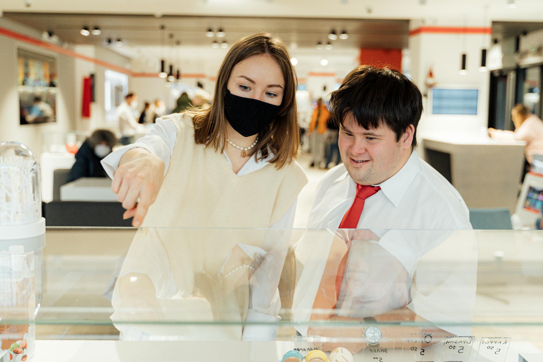 Klient wybiera produkty w przytulnej kawiarni, obsługa w maseczce