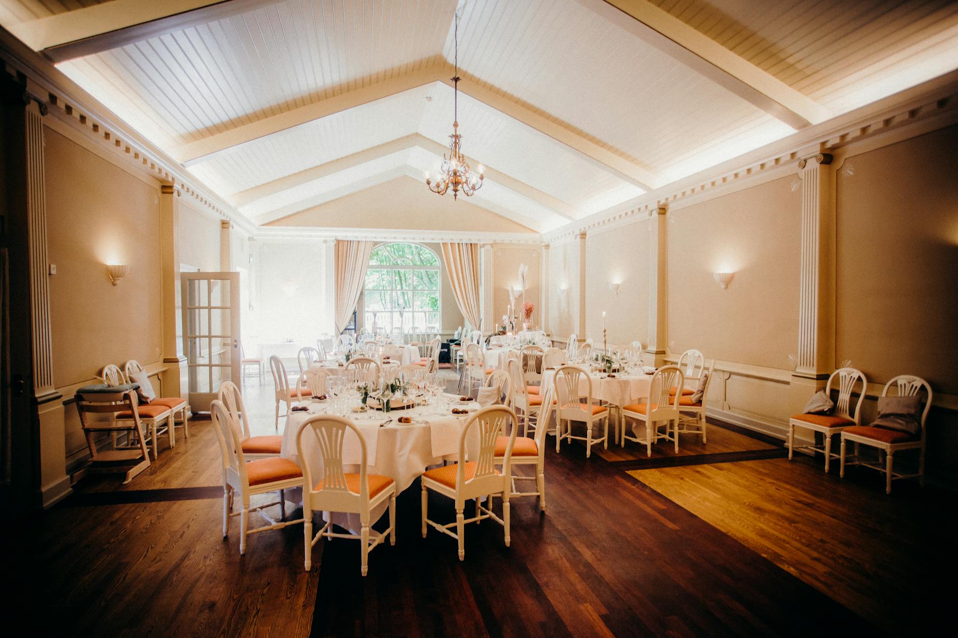 Elegancko udekorowana sala weselna z okrągłymi stołami i ciepłym światłem