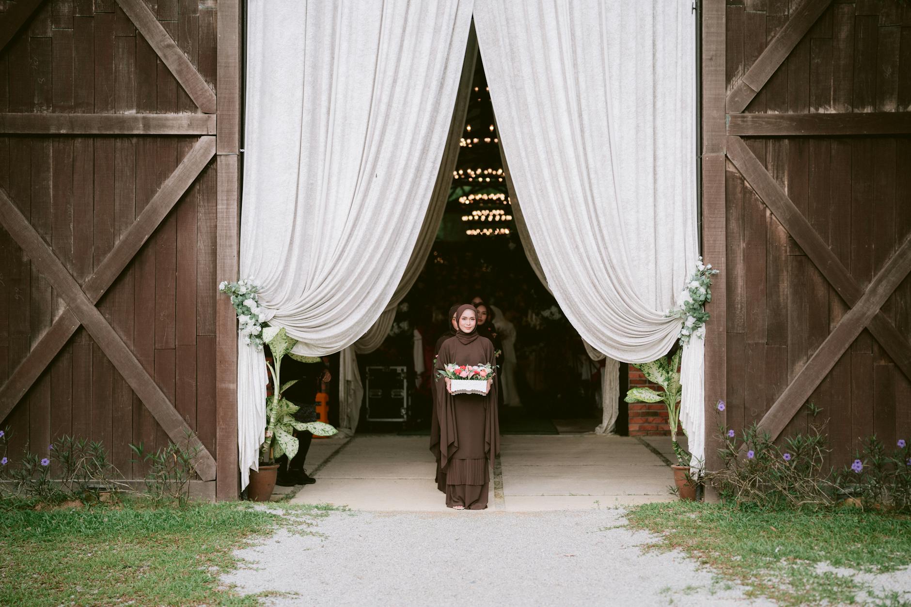 Kobieta z bukietem przy wejściu do rustykalnej sali weselnej