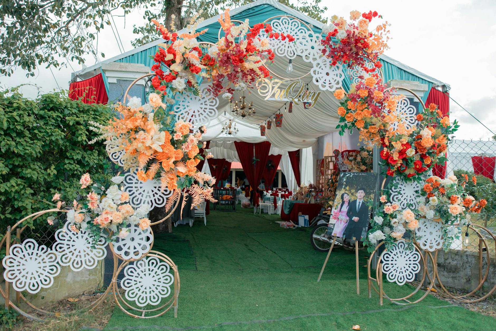 Kwiatowy łuk przy wejściu na plenerowe przyjęcie weselne