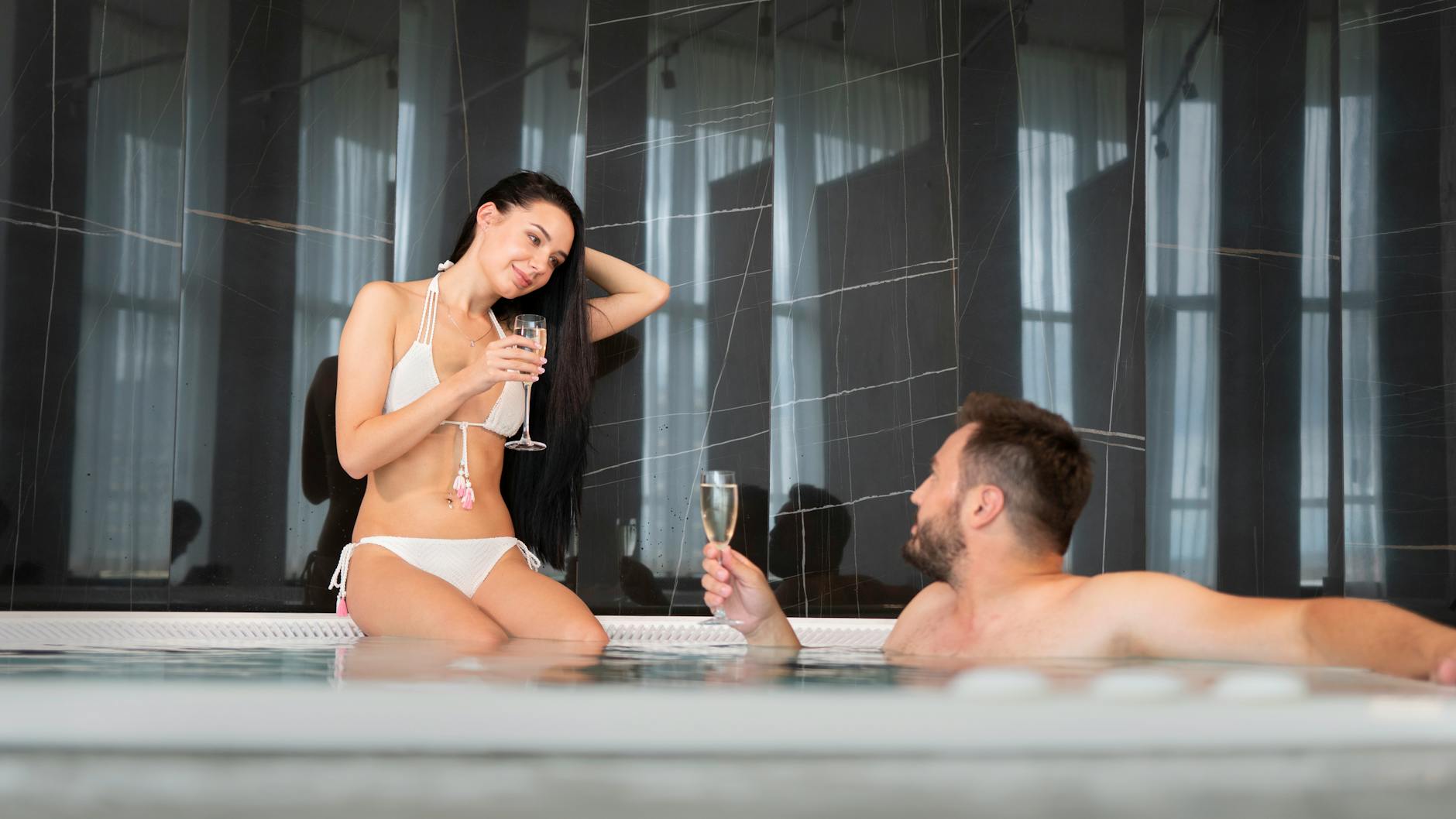 Młoda para z szampanem relaksuje się w jacuzzi w górskim hotelu SPA