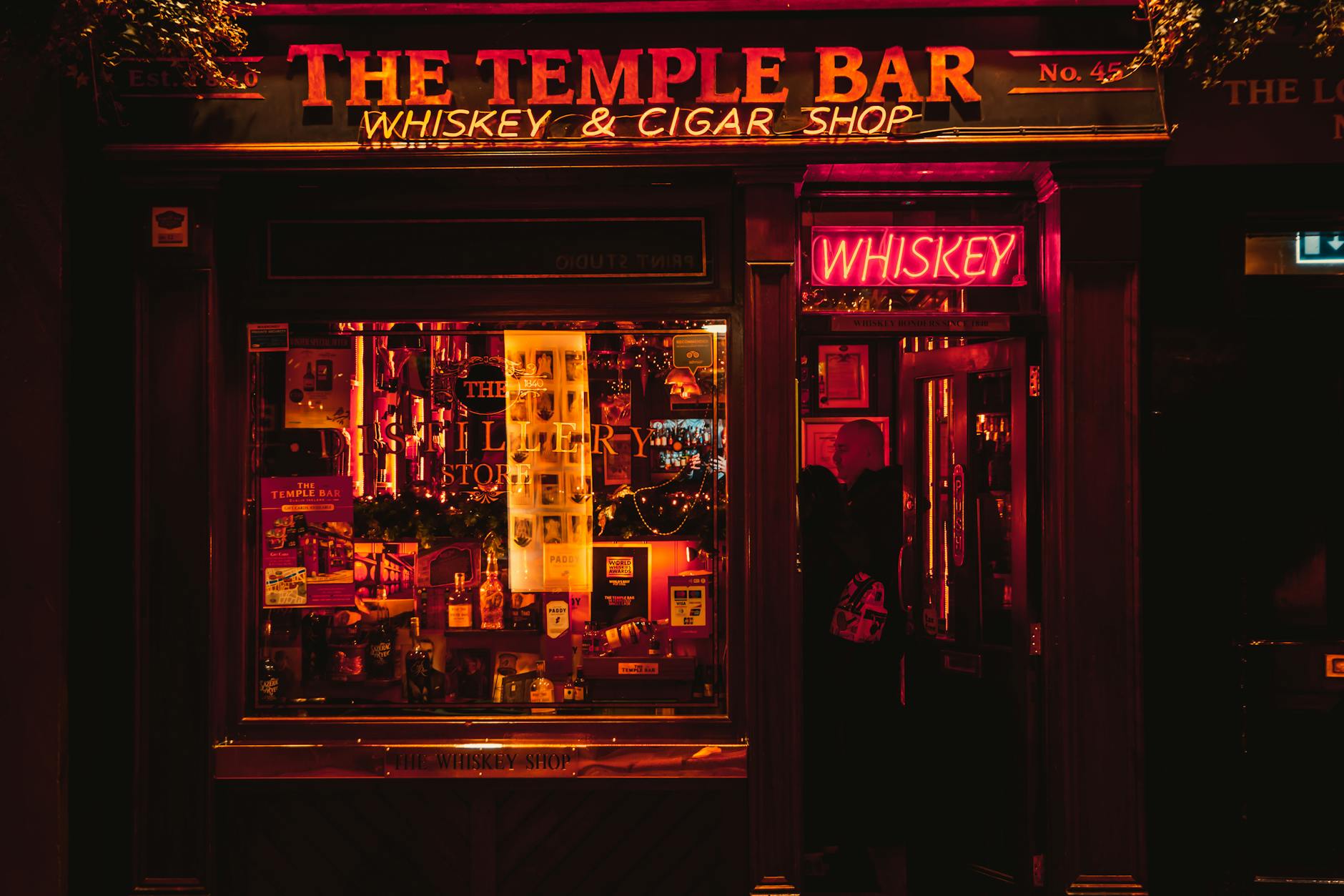 Nocny Temple Bar w Dublinie w blasku neonów, puby i sklep z whiskey
