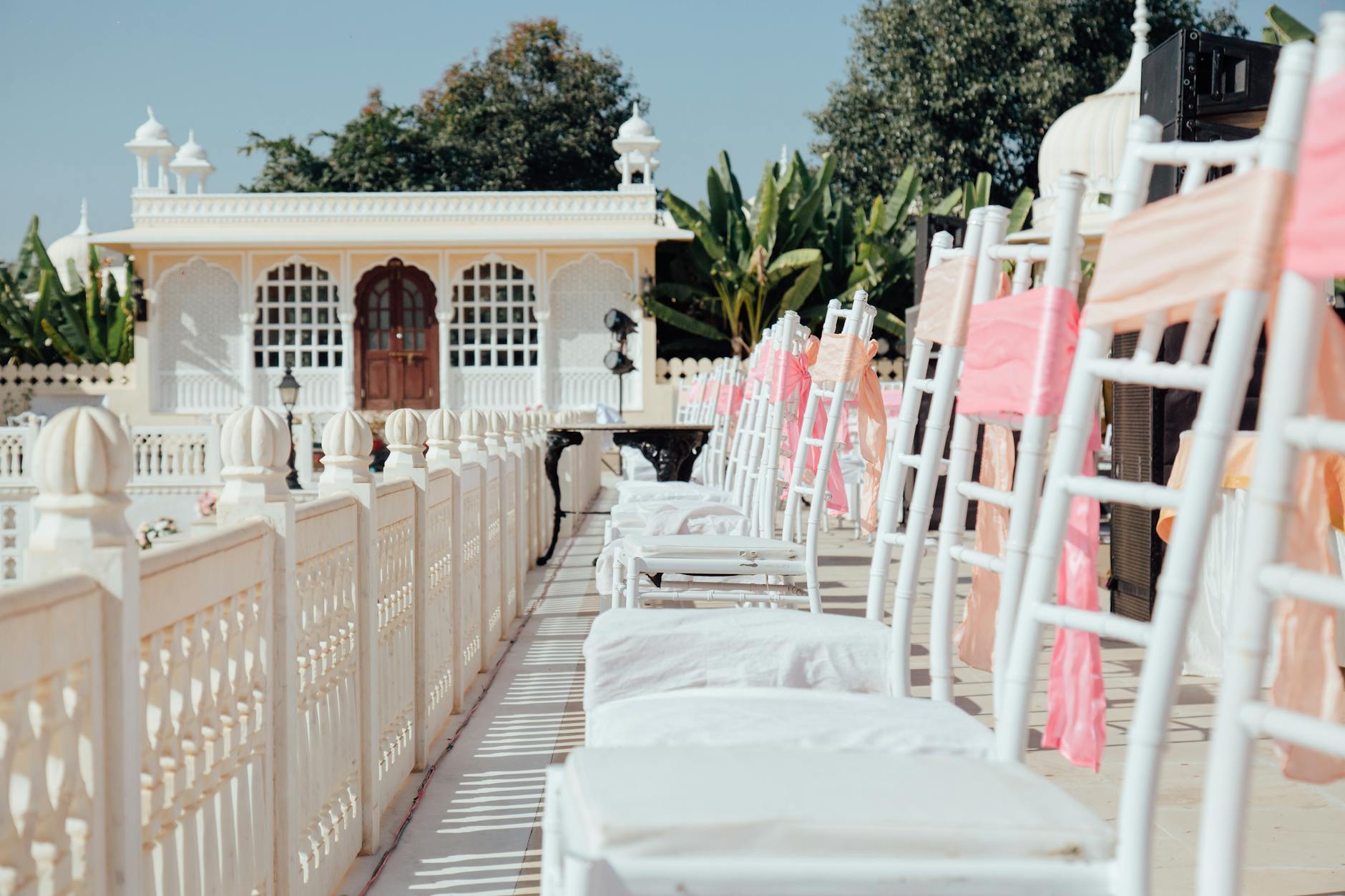 Plenerowa ceremonia ślubna z białymi krzesłami i pastelowymi dekoracjami