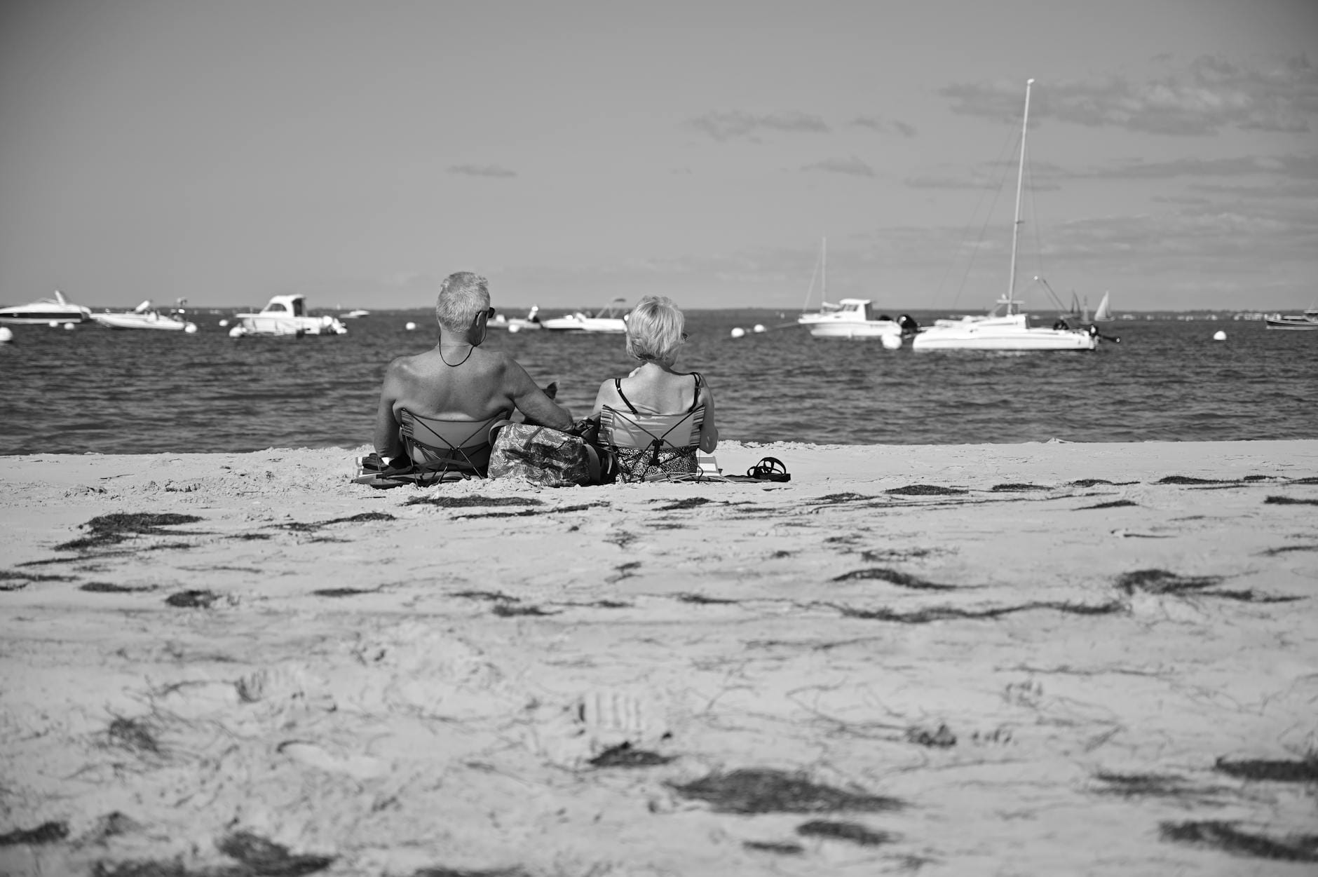 Starsze małżeństwo siedzi na plaży i spokojnie patrzy na morze