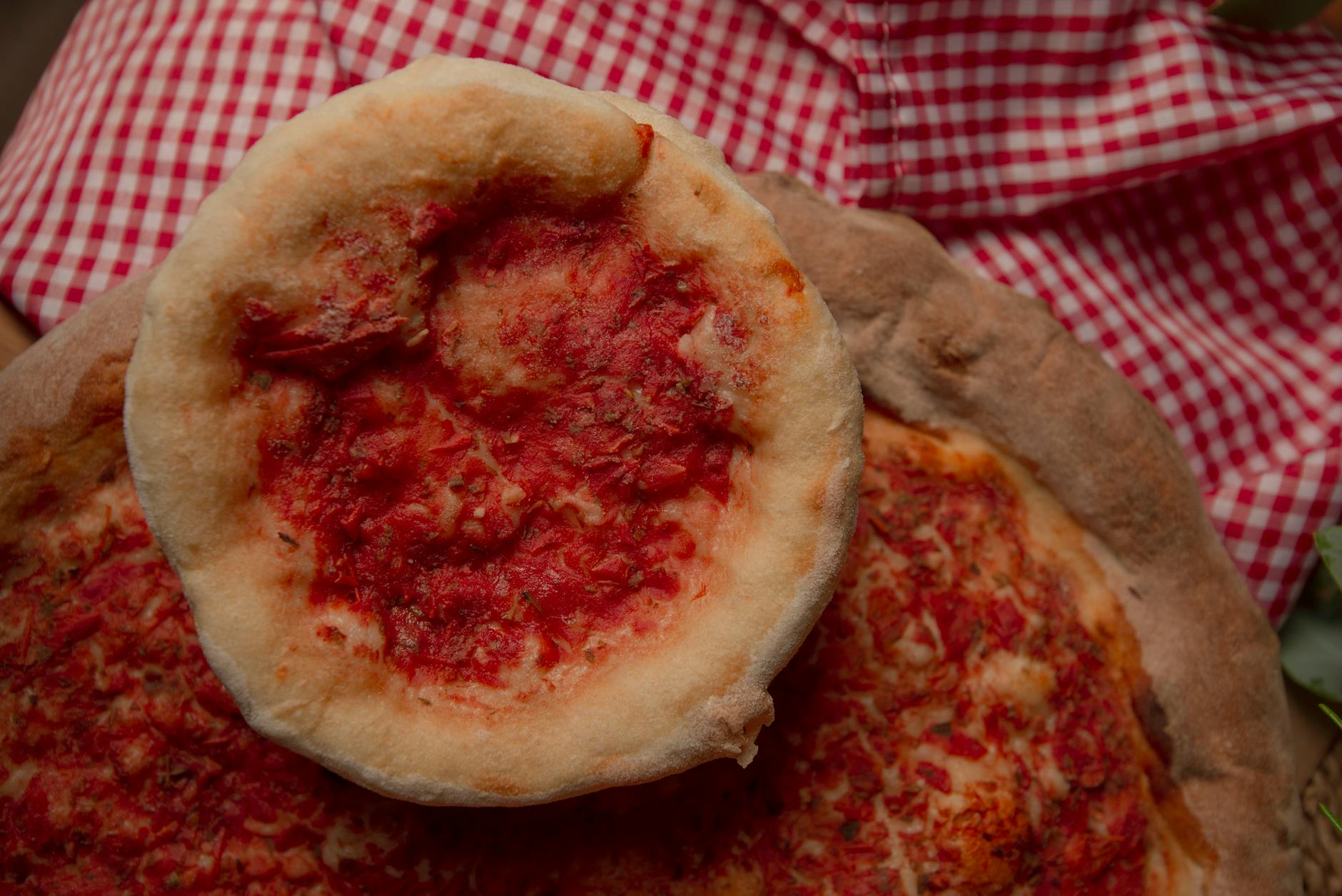 Domowe rustykalne pizze z sosem pomidorowym na kraciastym obrusie