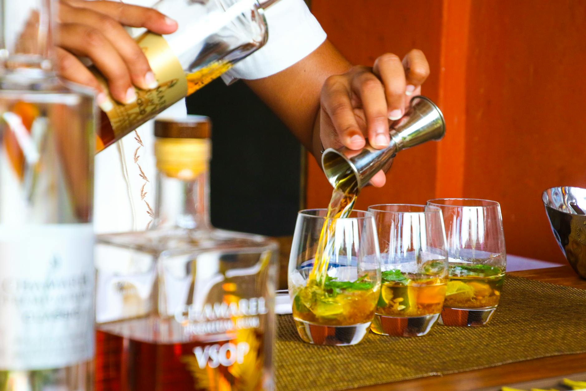 Barman nalewa kolorowe koktajle do szklanek na weselnym barze