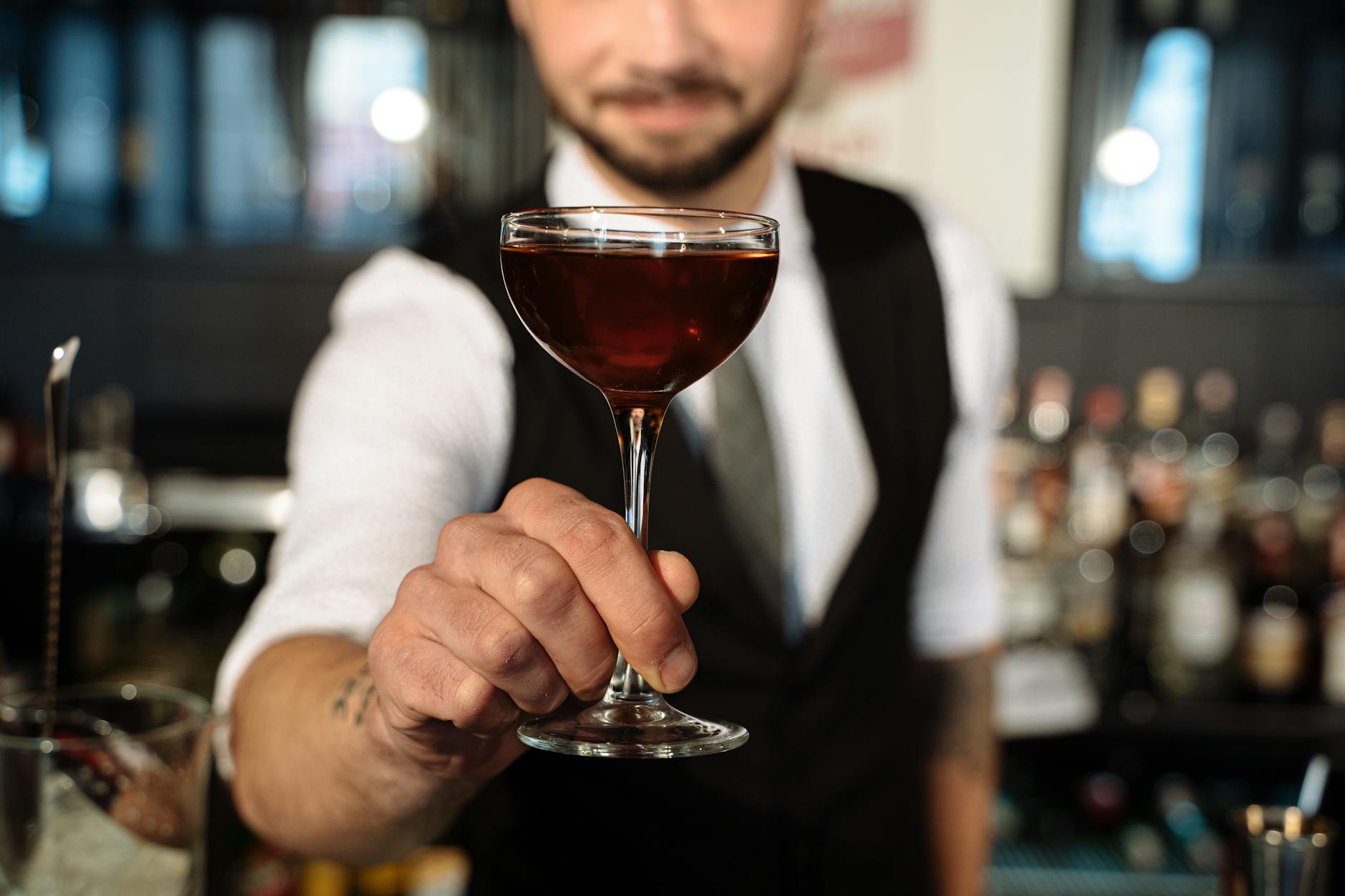 Barman podaje kolorowy koktajl w szklance podczas weselnego przyjęcia