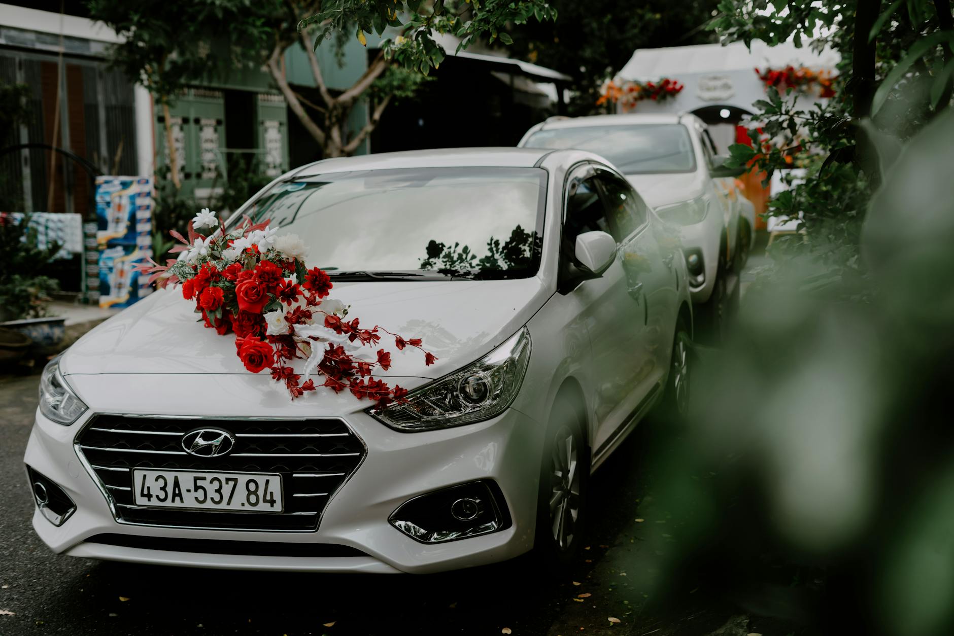 Białe auto Hyundai ozdobione czerwonymi kwiatami na ślub na zewnątrz