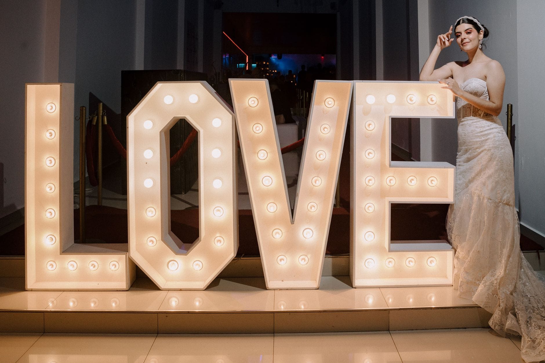 Panna młoda przy podświetlonym napisie LOVE na weselu glamour