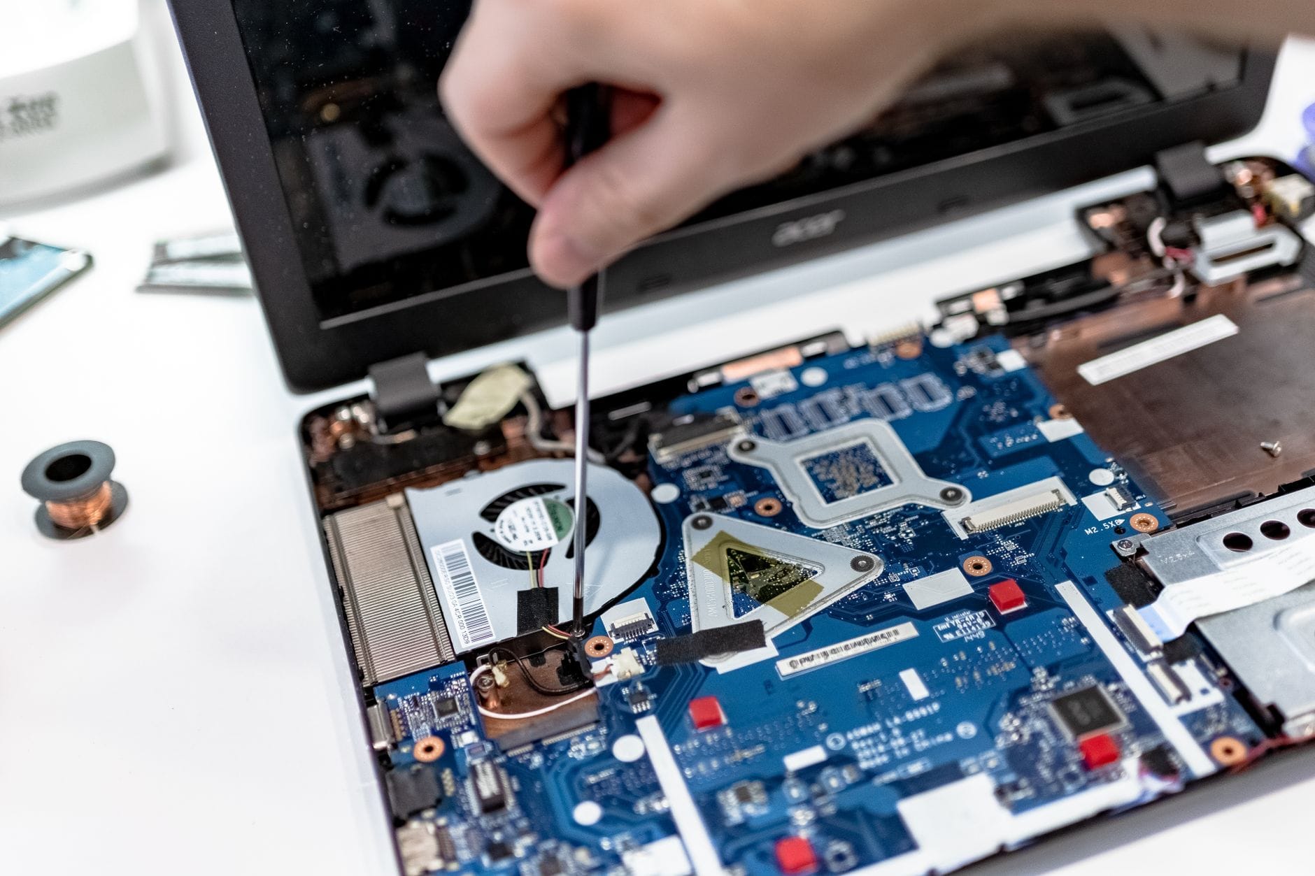 Serwisant naprawia płytę główną laptopa śrubokrętem