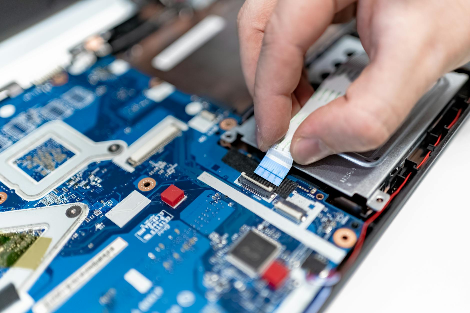 Serwisant naprawia płytę główną laptopa Toshiba zbliżenie dłoni i elektroniki Serwisant naprawia płytę główną laptopa Toshiba zbliżenie dłoni i elektroniki