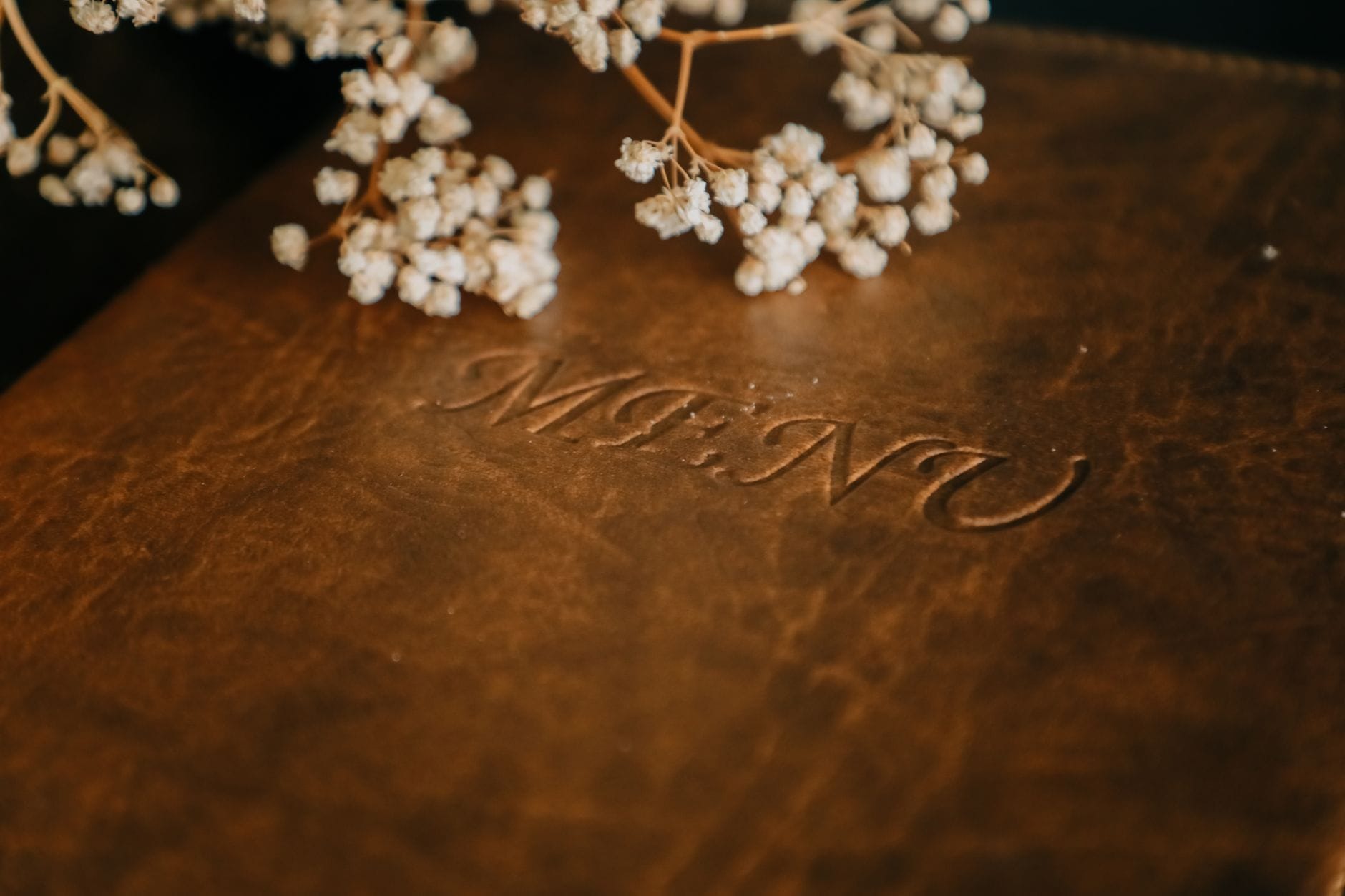 Brązowe skórzane menu z gipsówką na stole podczas degustacji weselnej