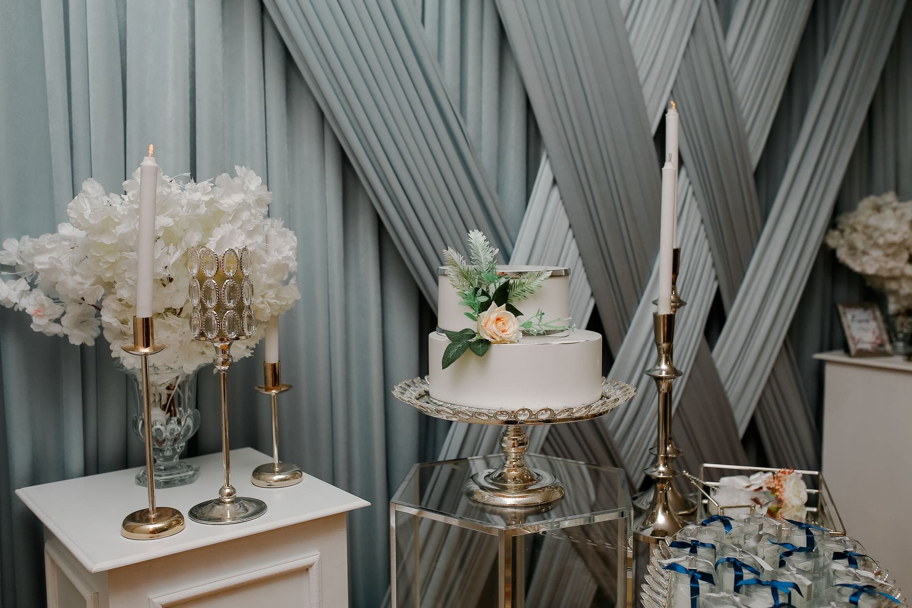 Elegancki weselny stół z kwiatowym tortem i świecami w srebrnych detalach Elegancki weselny stół z kwiatowym tortem i świecami w srebrnych detalach