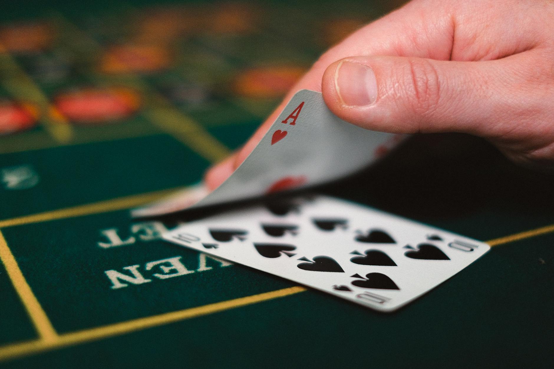 Karty do gry i ręka na stole kasyna podczas rozgrywki blackjacka