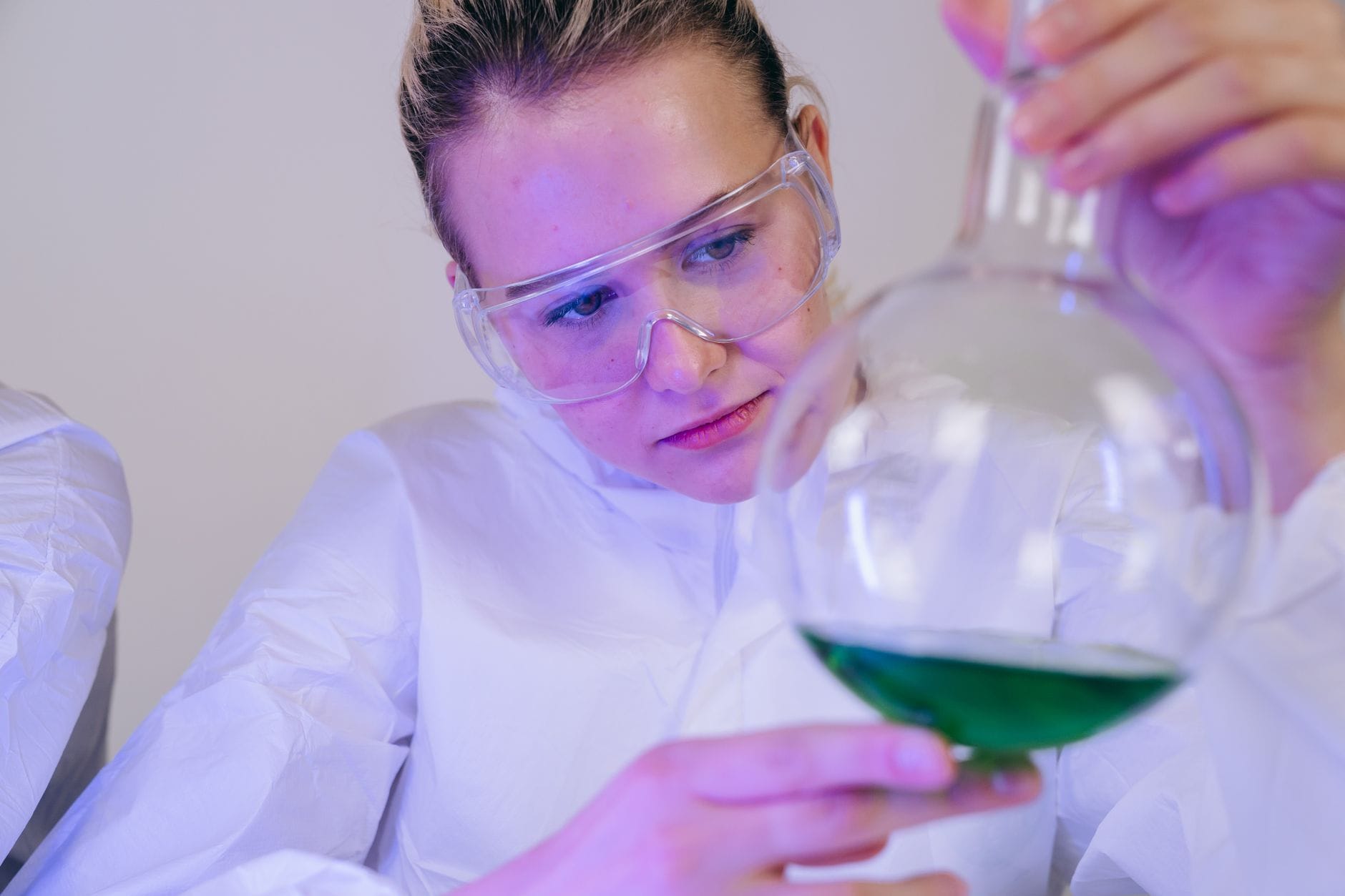 Studentka w laboratorium analizuje zielony roztwór w probówce Studentka w laboratorium analizuje zielony roztwór w probówce