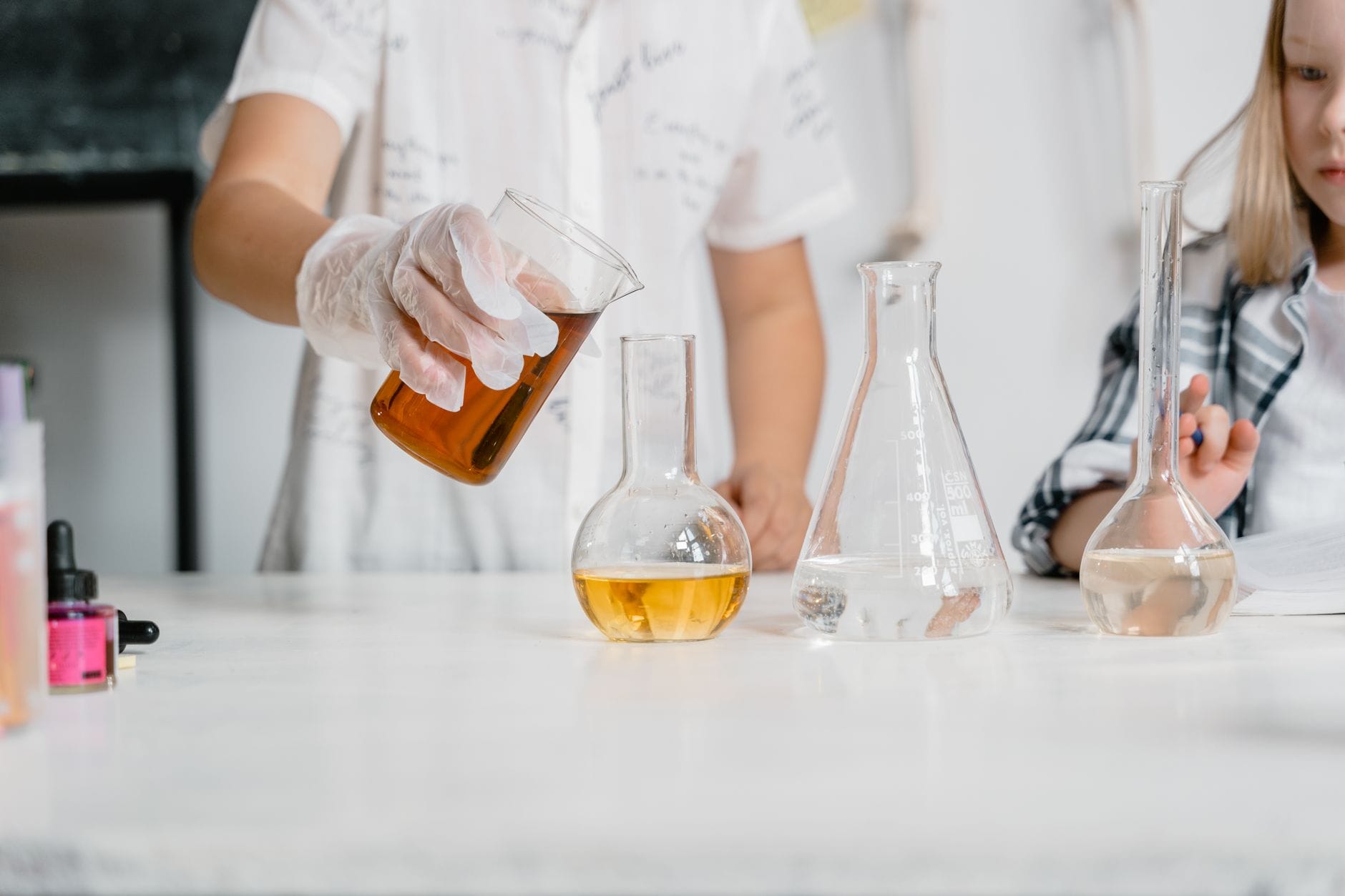 Uczniowie w laboratorium wykonują doświadczenie chemiczne z odczynnikami