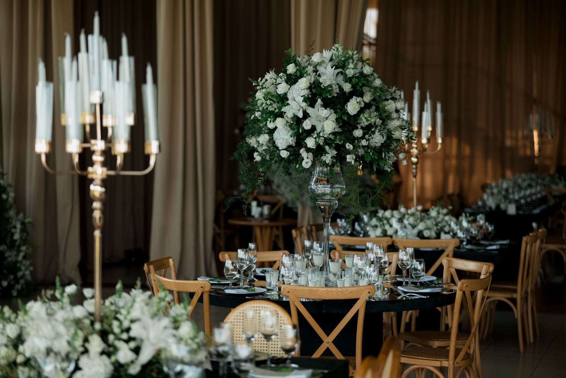 Sala weselna z bogatą florystyką i kandelabrami na eleganckich stołach
