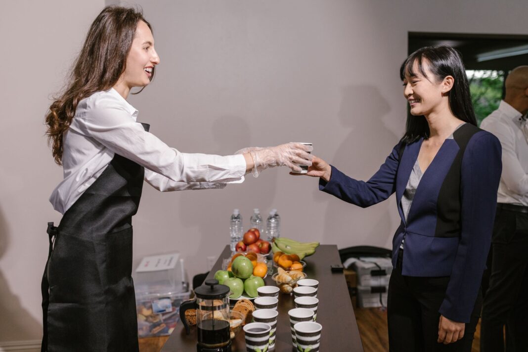 Dwie osoby rozmawiają przy kawie i owocach podczas cateringu Dwie osoby rozmawiają przy kawie i owocach podczas cateringu